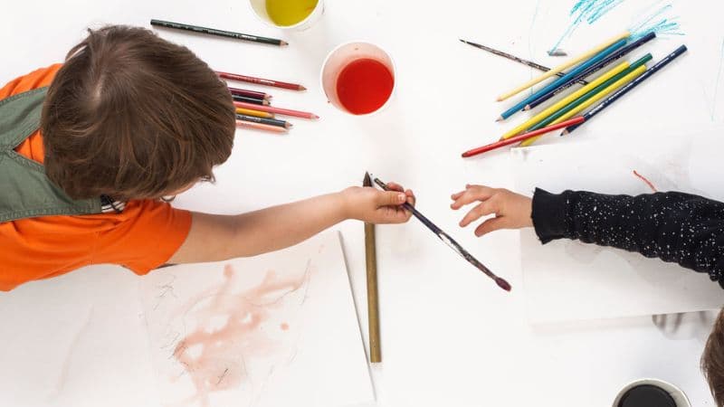 子どもが絵具で絵を描いている
