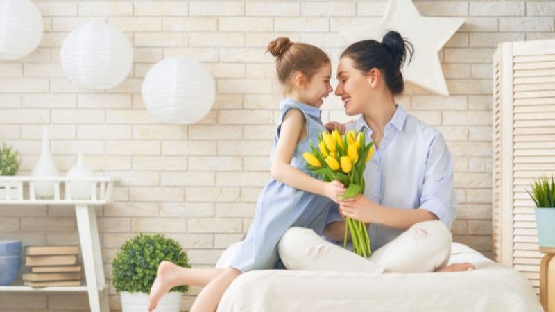 女の子がお母さんに黄色いチューリップの花束を上げている画像